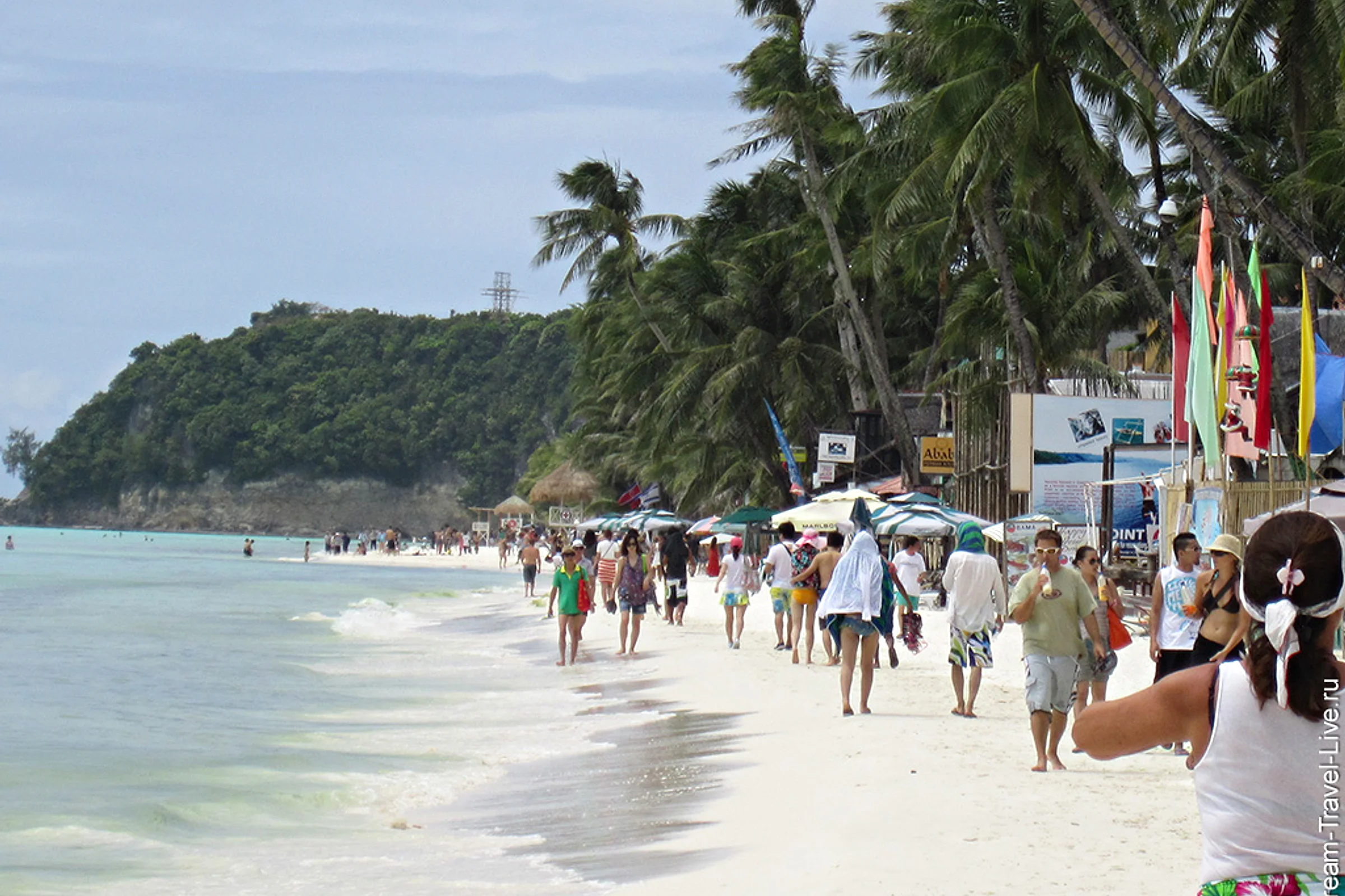 Люди идут вдоль воды на оживлённом участке White Beach